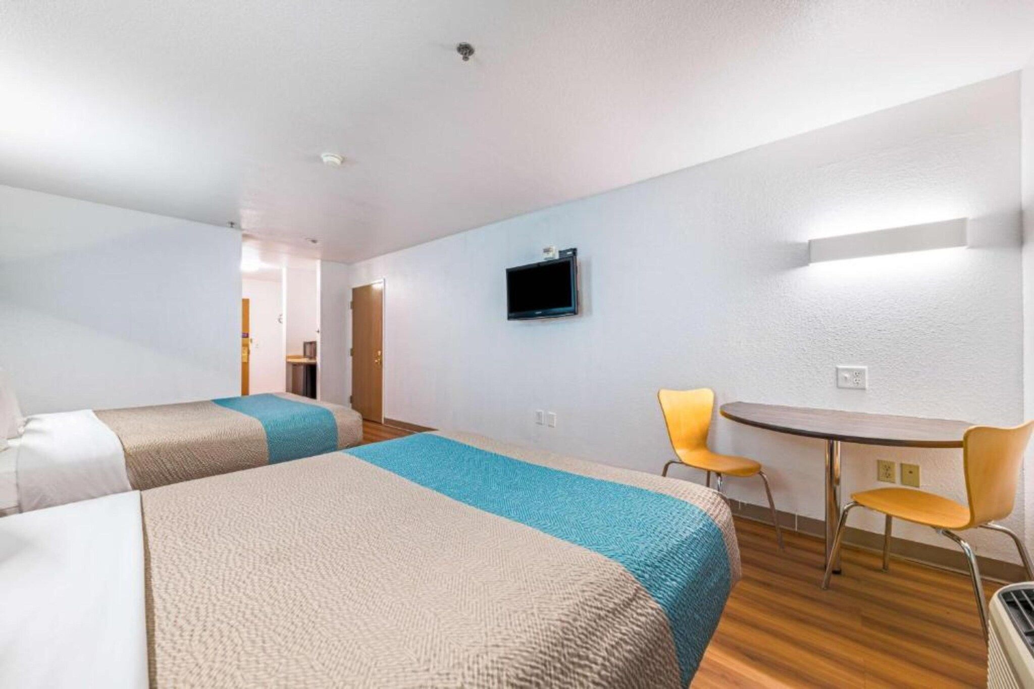 Une chambre d’hôtel avec deux lits, un bureau, une chaise et un téléviseur.