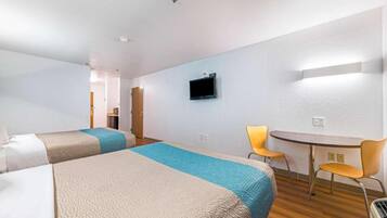 Une chambre d’hôtel avec deux lits, un bureau, une chaise et un téléviseur.