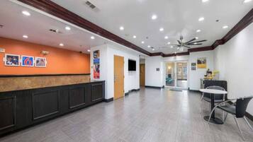 A spacious lobby with a reception desk, seating area, and a ceiling fan.
