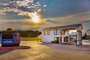 A building with a welcoming sign, a covered entrance, and a parking area.