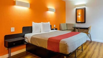A hotel room with a bed, bedside tables, a desk, and a chair.