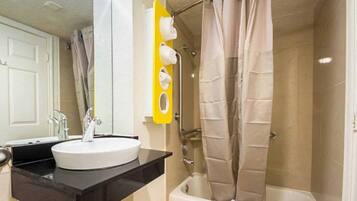 A bathroom with a white sink, a black countertop, a yellow towel rack, and a shower curtain.