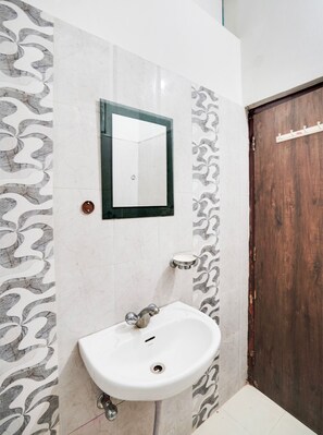 Un baño con un lavabo blanco, un espejo y una puerta de madera.