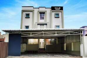 Hotel com entrada coberta, escadaria que leva ao edifício principal e placa indicando ser um hotel de serviço corporativo.