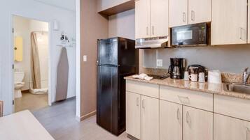 A compact kitchen with a refrigerator, microwave, coffee maker, and a sink.