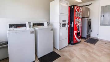 A laundry room with two washing machines, a dryer, and a vending machine.