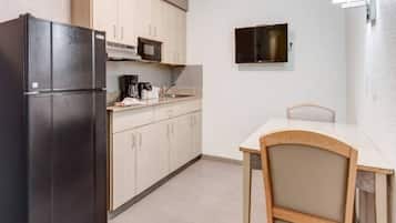 Cocina compacta con refrigerador, microondas y una pequeña mesa de comedor con una silla.