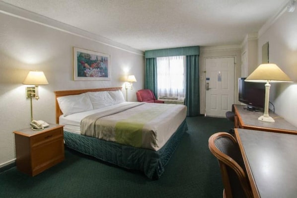 Een hotelkamer met een bed, nachtkastjes, een bureau, een stoel, een televisie en een schilderij aan de muur.