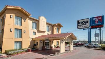 Een hotel met een entree met rode dakpannen, een overdekt terras, en een bord met 'iHop Restaurant' en 'Studio 6 Extended Stay'.
