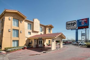 Een hotel met een entree met rode dakpannen, een overdekt terras, en een bord met 'iHop Restaurant' en 'Studio 6 Extended Stay'.