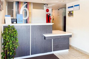 Un comptoir d’accueil avec un grand panneau indiquant le chiffre « 6 », un extincteur et un code QR imprimé sur une carte.