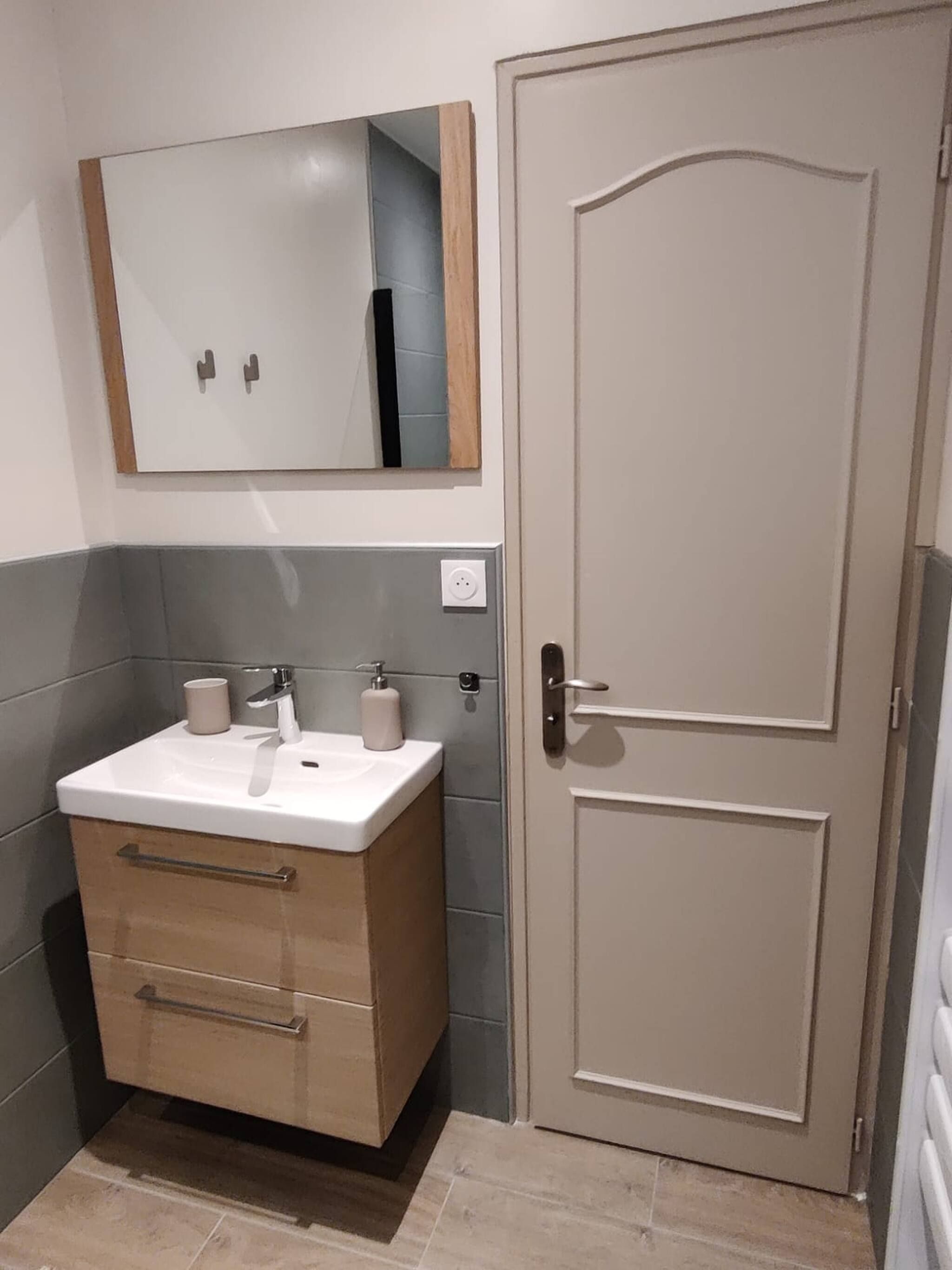 Une salle de bain avec un lavabo, un miroir et une porte.