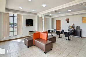 Eine Hotelhalle mit Sitzgelegenheiten, einem an der Wand montierten Fernseher und einer Rezeption mit Annehmlichkeiten.