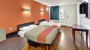 Ein Hotelzimmer mit zwei Betten, einem Schreibtisch, einem Sessel und einem Fernseher.