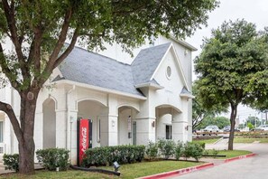 A building with a white facade, a grey roof, and a Coca-Cola sign. - Comfy 1 QUEEN BED | SMOKING (GRAND PRAIRIE)