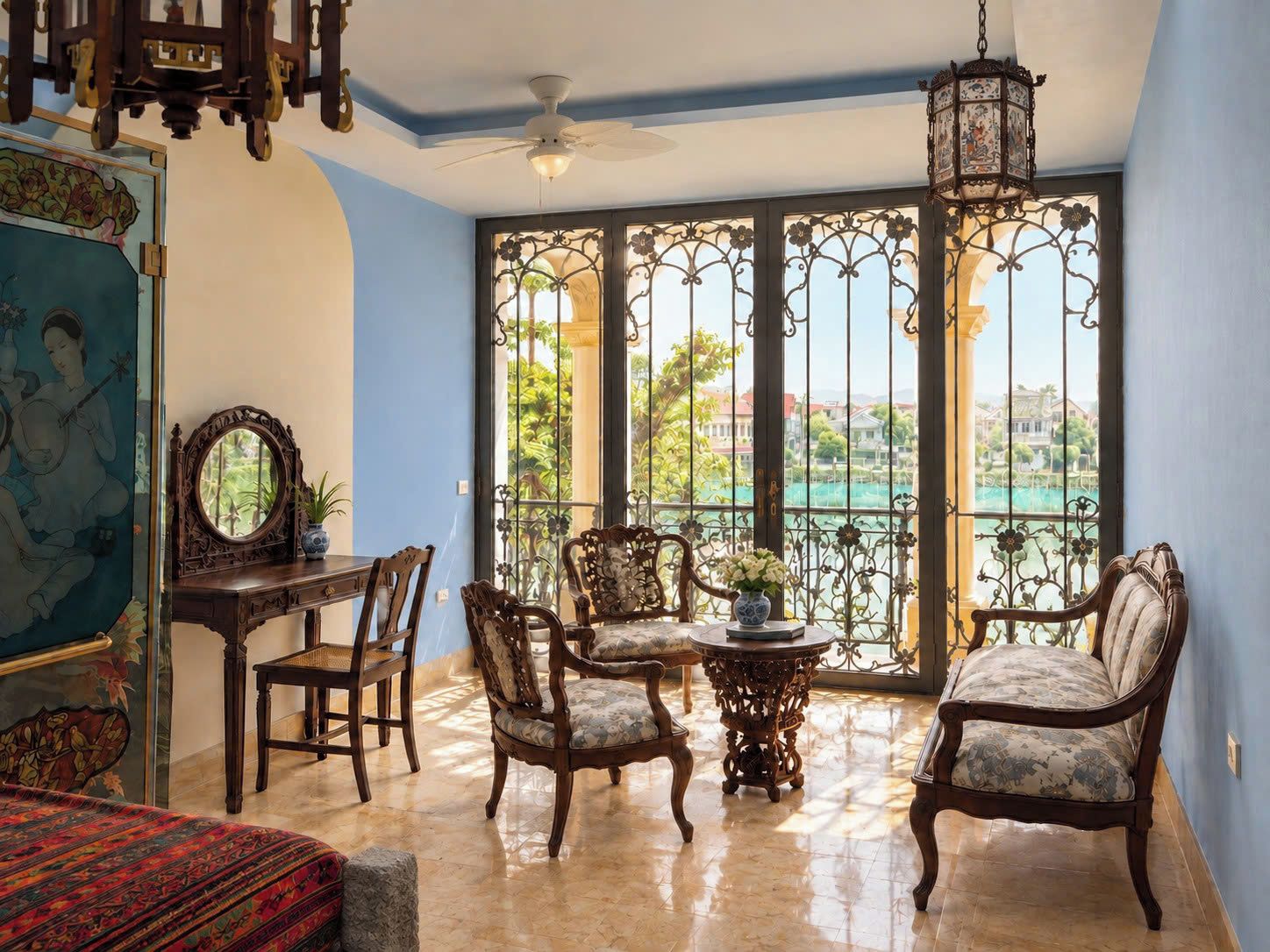 A room with a balcony, a ceiling fan, a table with chairs, and a view of a body of water and greenery.