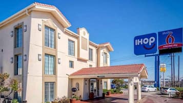 Een hotel met een overdekte ingang, een parkeerplaats en een bord met I-HOP 6 extended stay.