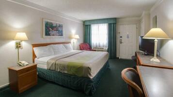 Een hotelkamer met een bed, nachtkastjes, een bureau, een stoel, een televisie en een schilderij aan de muur.