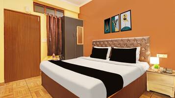 A hotel room with a large bed, a wardrobe, a nightstand with a lamp, and a wall with three framed pictures.