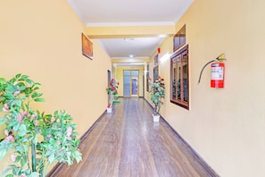 A hallway with wooden flooring, yellow walls, and potted plants. - Hotel O Vidhan Sabha Chowk (Dehradun)