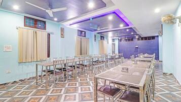 A dining area with multiple tables and chairs, ceiling fans, and patterned flooring.