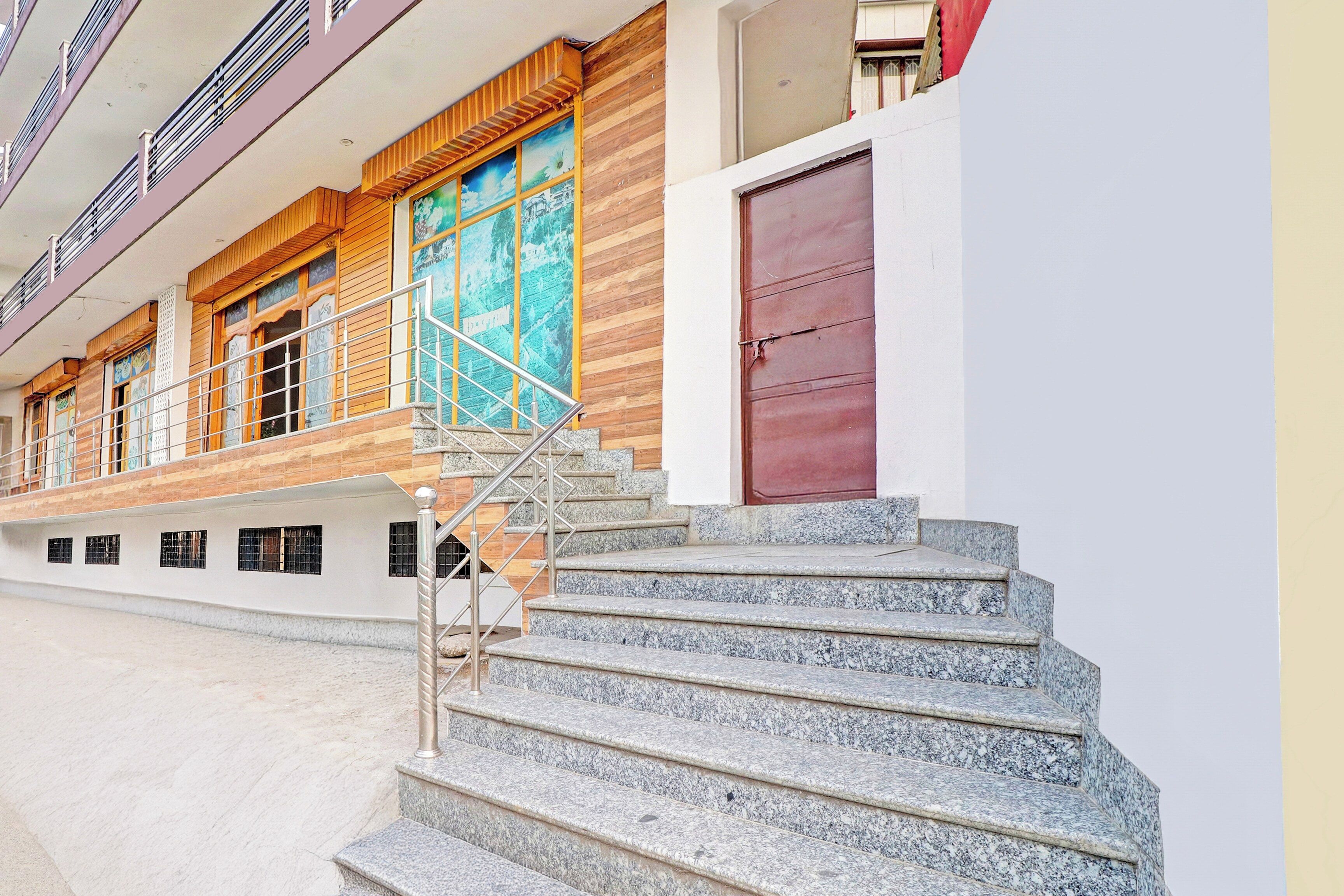 Un edificio con una escalera que lleva a una puerta, una ventana con vistas y un balcón con barandillas.