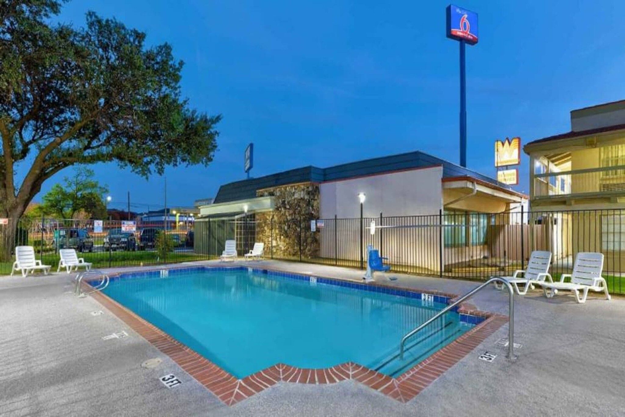 A swimming pool with lounge chairs and a building with a sign in the background.