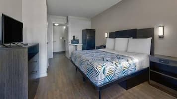 A hotel room with a bed, bedside tables, a television, a wardrobe, and a bathroom visible through an open door.