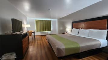 Een hotelkamer met een bed, een bureau, een stoel, een televisietoestel en een raam met gordijnen.