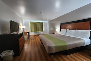 A hotel room with a bed, a desk, a chair, a television, and a window with curtains.