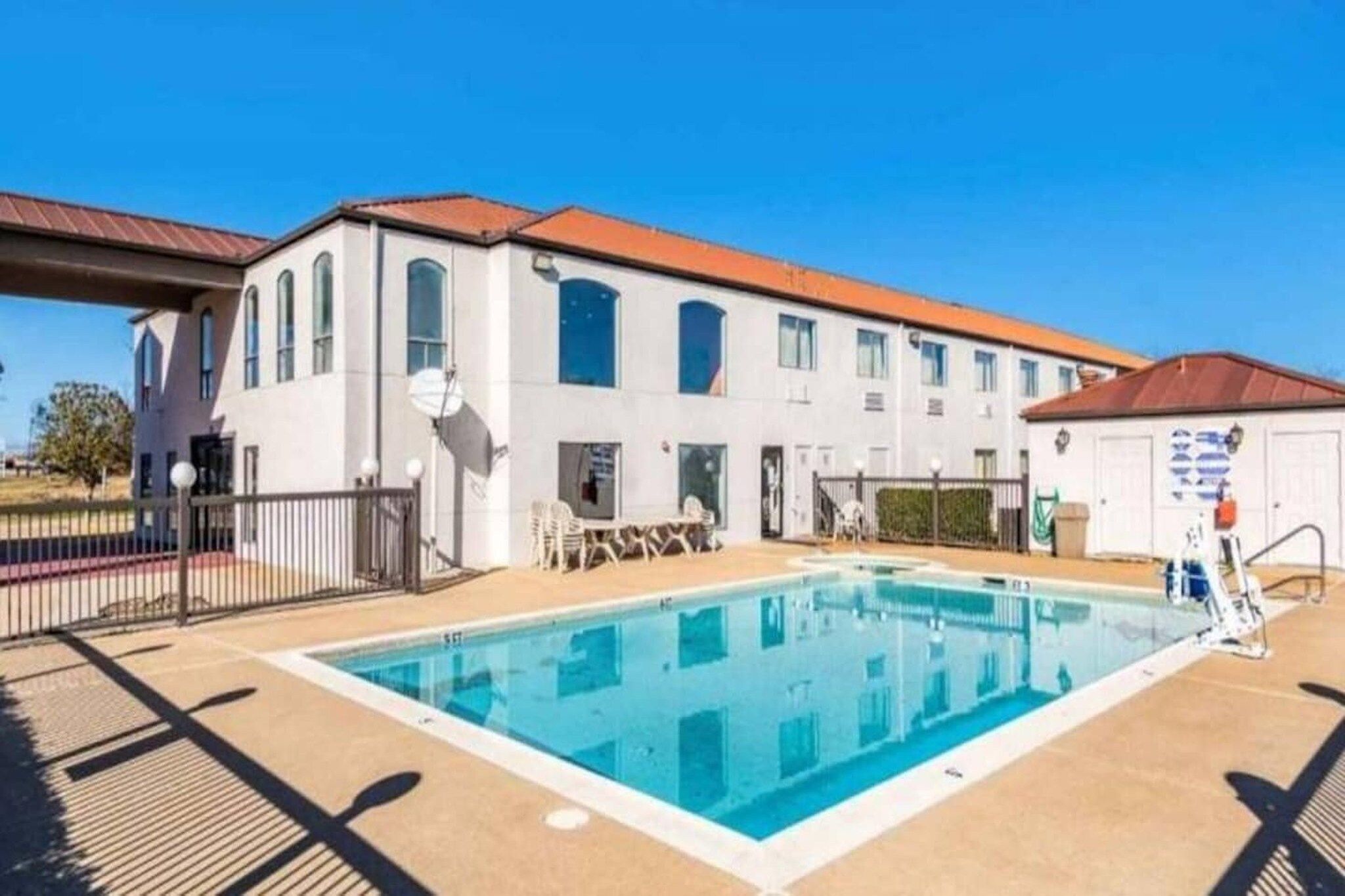 A building with a swimming pool, outdoor seating, and a fenced area.