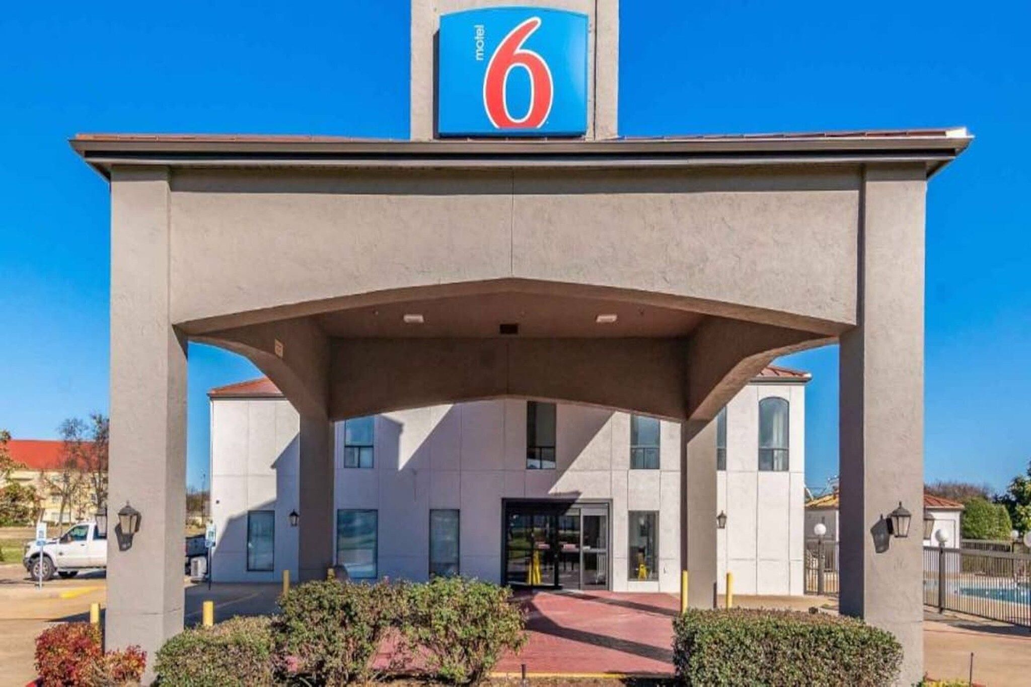 A motel with a prominent '6' sign, a covered entrance, and a parking lot.