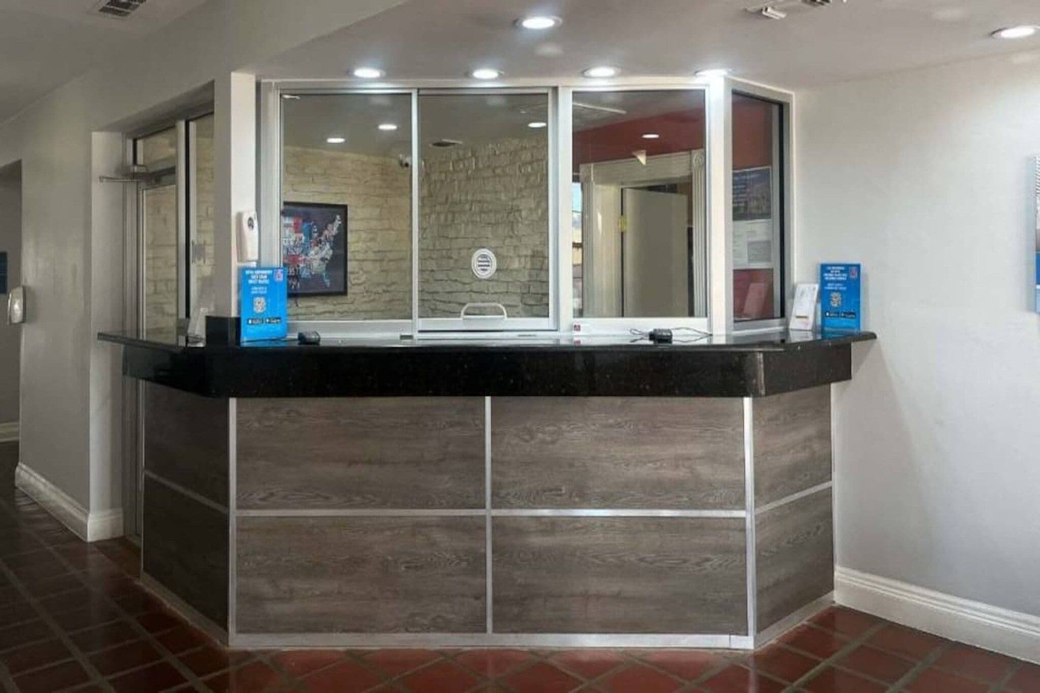 Una recepción con una estructura de vidrio, una pared de piedra al fondo y un piso de baldosas.