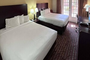 A hotel room with two beds, a desk, and a window with curtains. - 2 Queen Beds | Non-Smoking (Dallas)