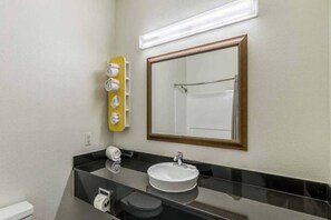 A bathroom with a black countertop, a white sink, a mirror with a wooden frame, and a yellow soap dispenser. - Comfy 2 Queen Beds | Non-Smoking (NORTH RICHLAND HILLS)