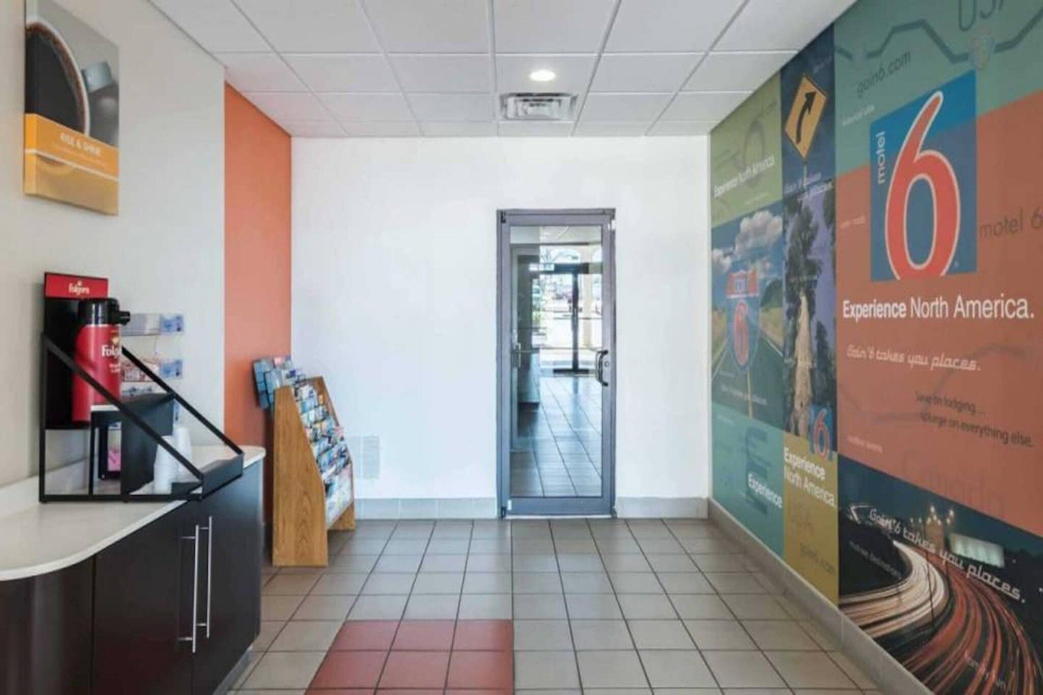 A reception area with a counter, a magazine rack, and a door leading to a hallway.
