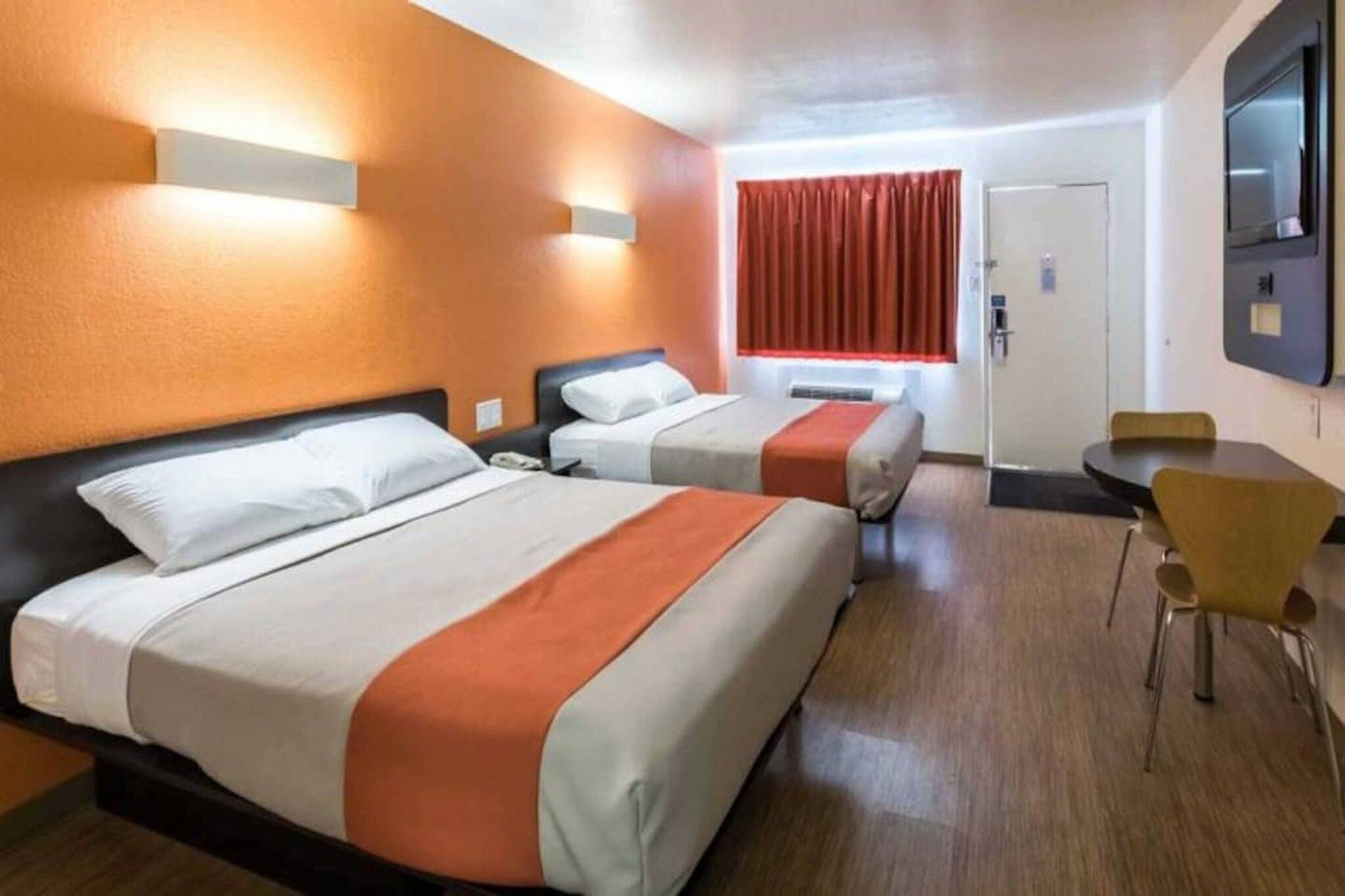 A hotel room with two beds, a desk, and a chair.