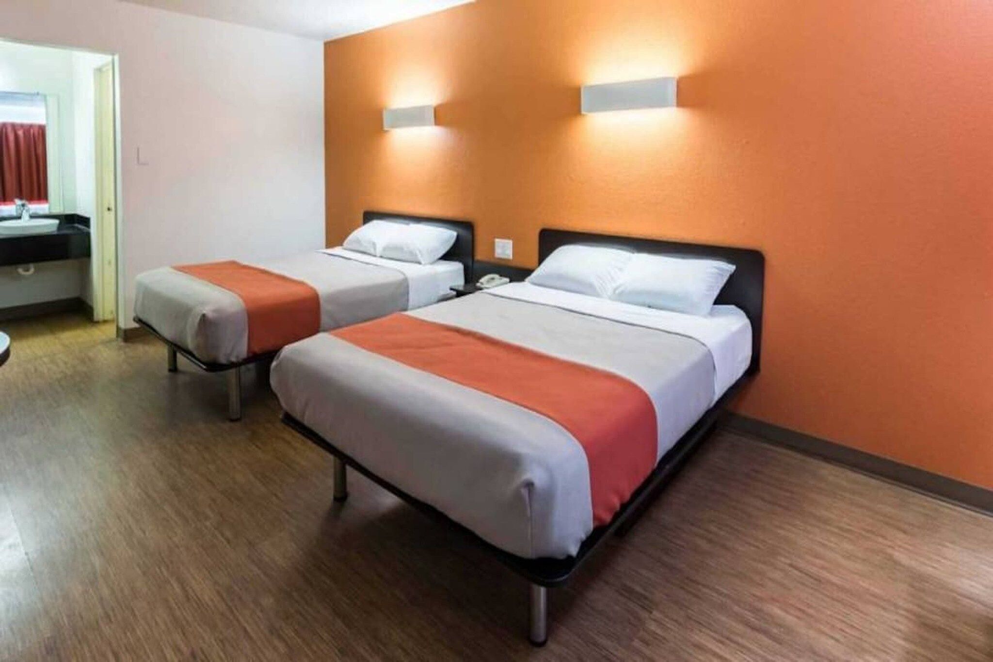 A hotel room with two beds, a bathroom, and a view of the street.