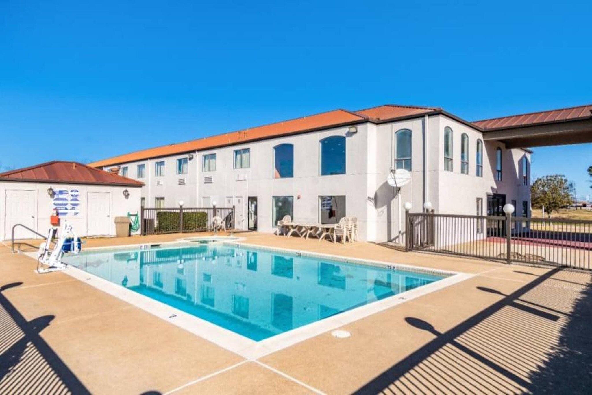 A swimming pool with a clear blue water surface, surrounded by a tiled deck area.