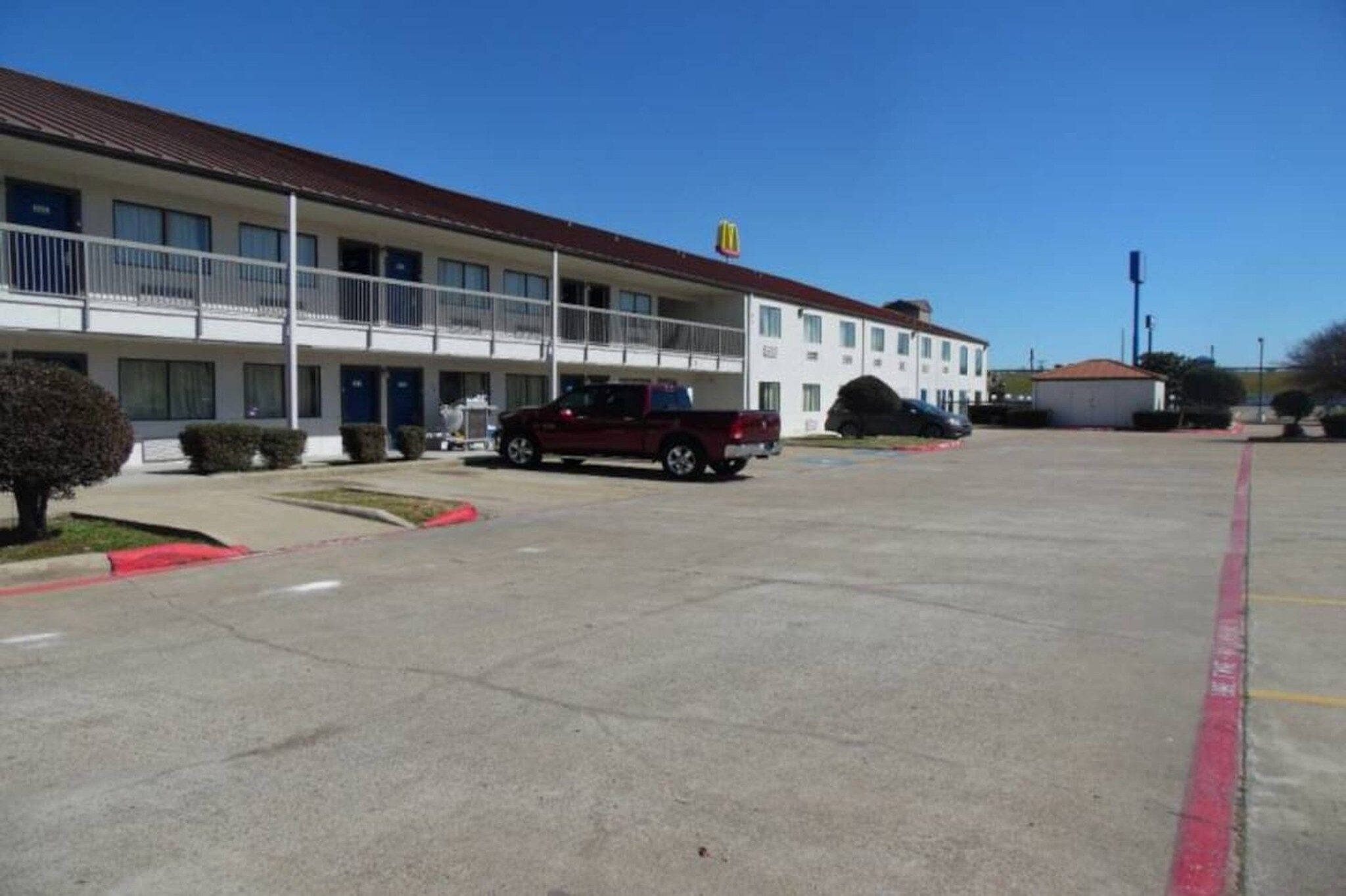 A motel with a parking lot, a red pickup truck, and a McDonald's sign.