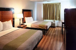 A hotel room with two beds, a desk, a chair, a lamp, and a window with curtains. - 2 Queen Beds | Smoking (Ennis)