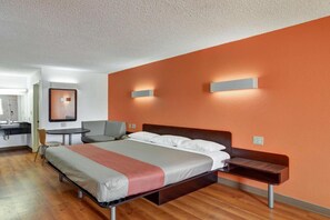 Ein modernes Hotelzimmer mit einem Bett, einem Nachttisch und einem Schreibtisch mit Stuhl.