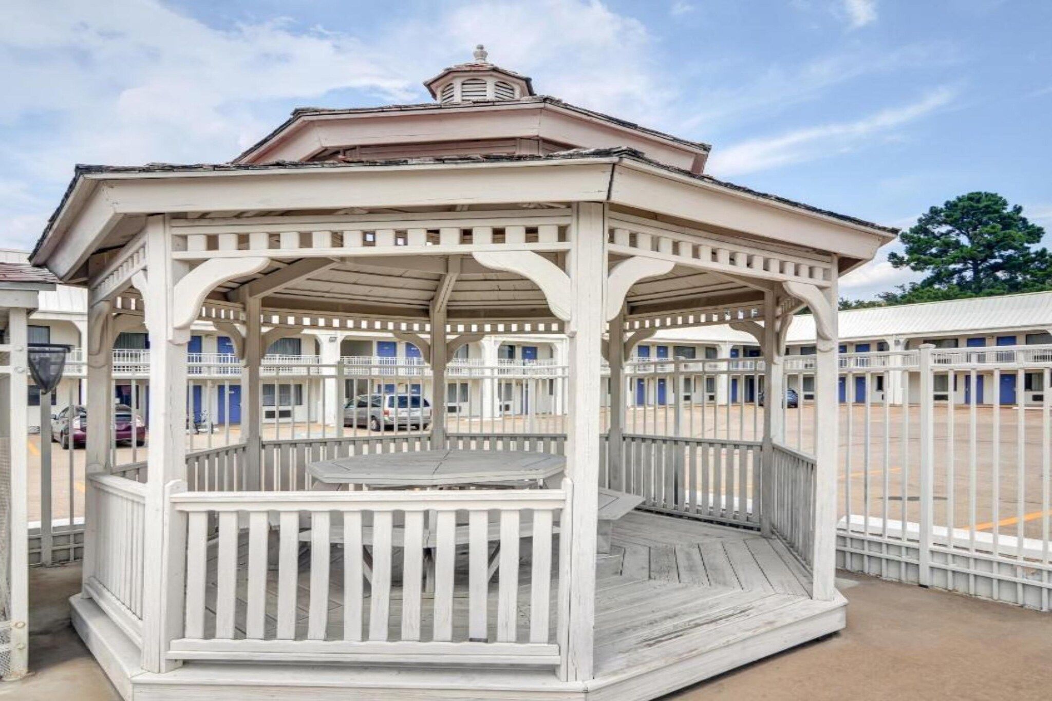 Ein Gazebo mit Holzdeck und Geländern, umgeben von einem Zaun.