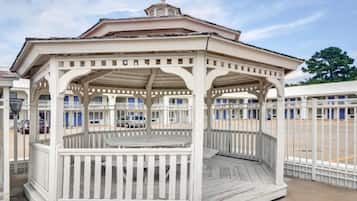Ein Gazebo mit Holzdeck und Geländern, umgeben von einem Zaun.