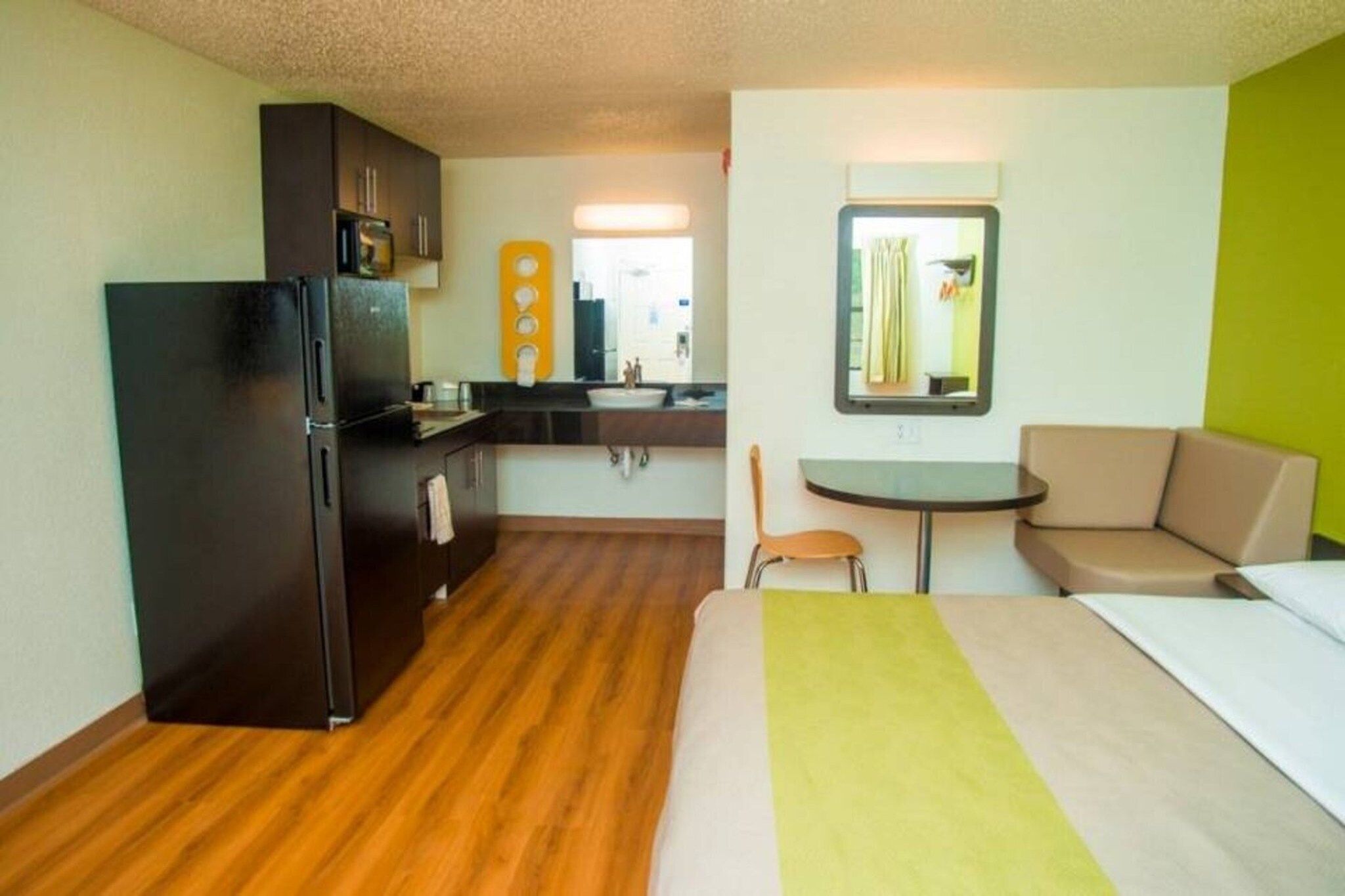 Ein kompaktes Hotelzimmer mit Küchenzeile, einem Bett, einem kleinen Esstisch und einem Schlafsofa.