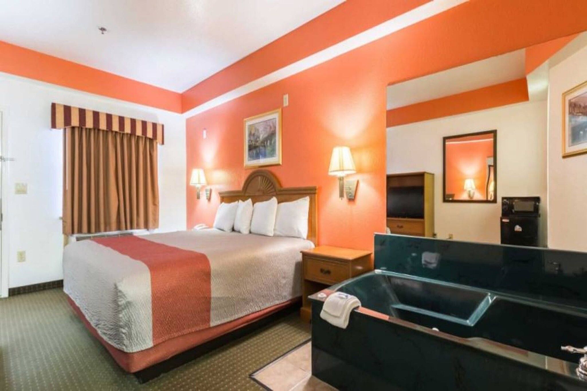 Une chambre d’hôtel comprenant un lit, des tables de chevet, un bureau, un miroir et une salle de bain.