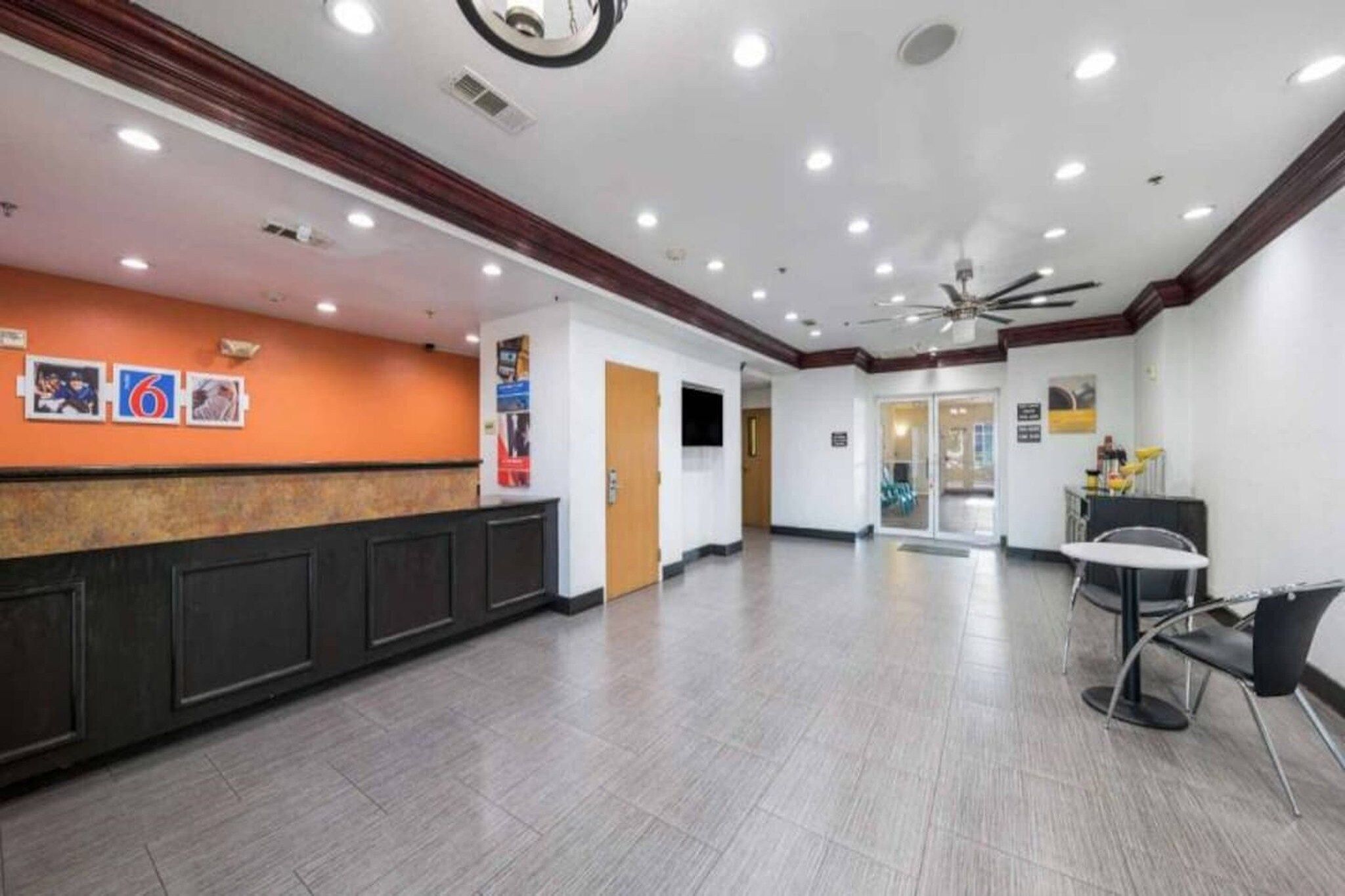A spacious lobby with a reception desk, seating area, and a ceiling fan.