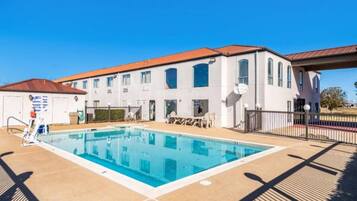 A swimming pool with a clear blue water surface, surrounded by a tiled deck area.