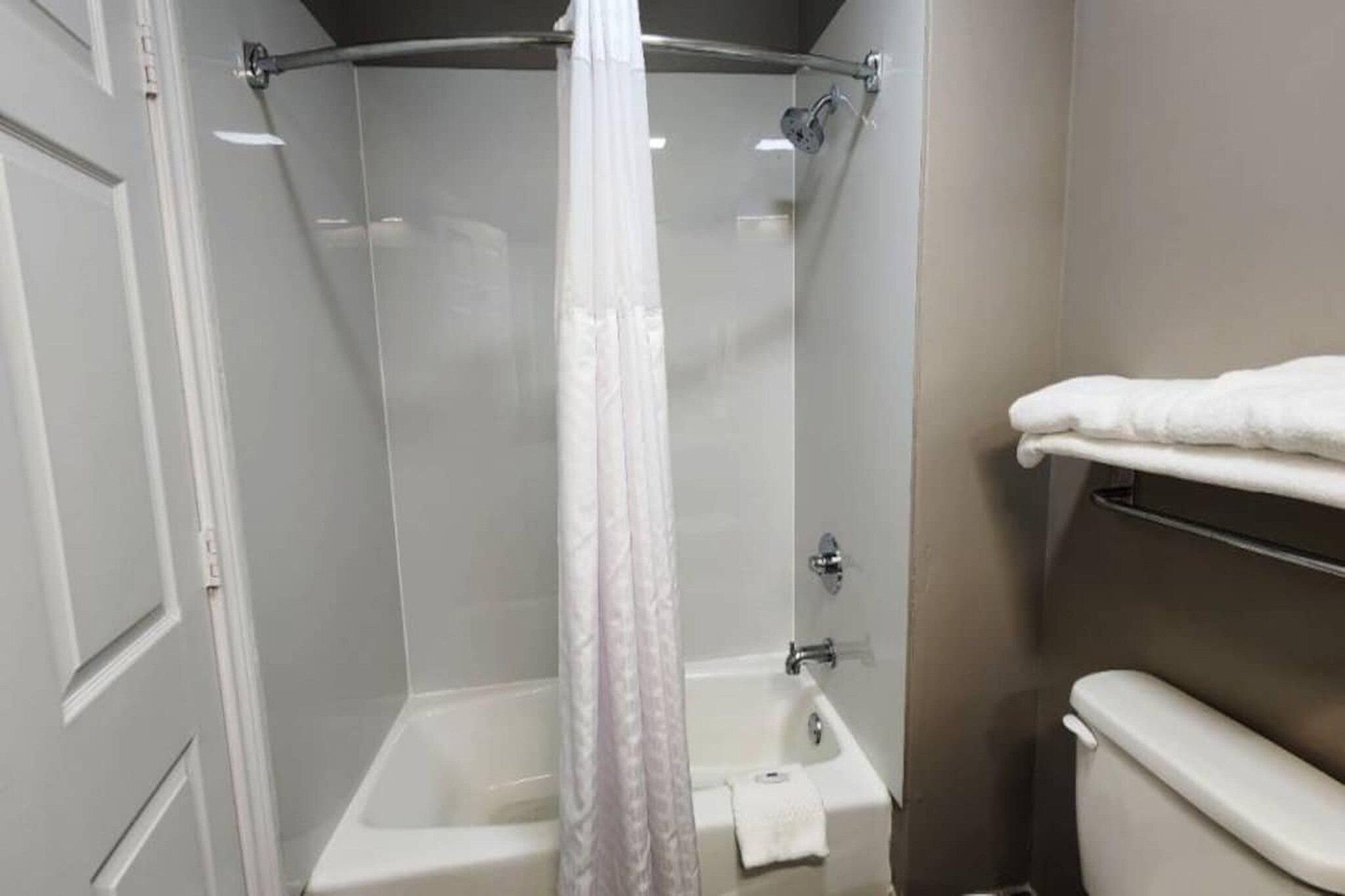 A shower with a glass door, a white towel rack, and a toilet.