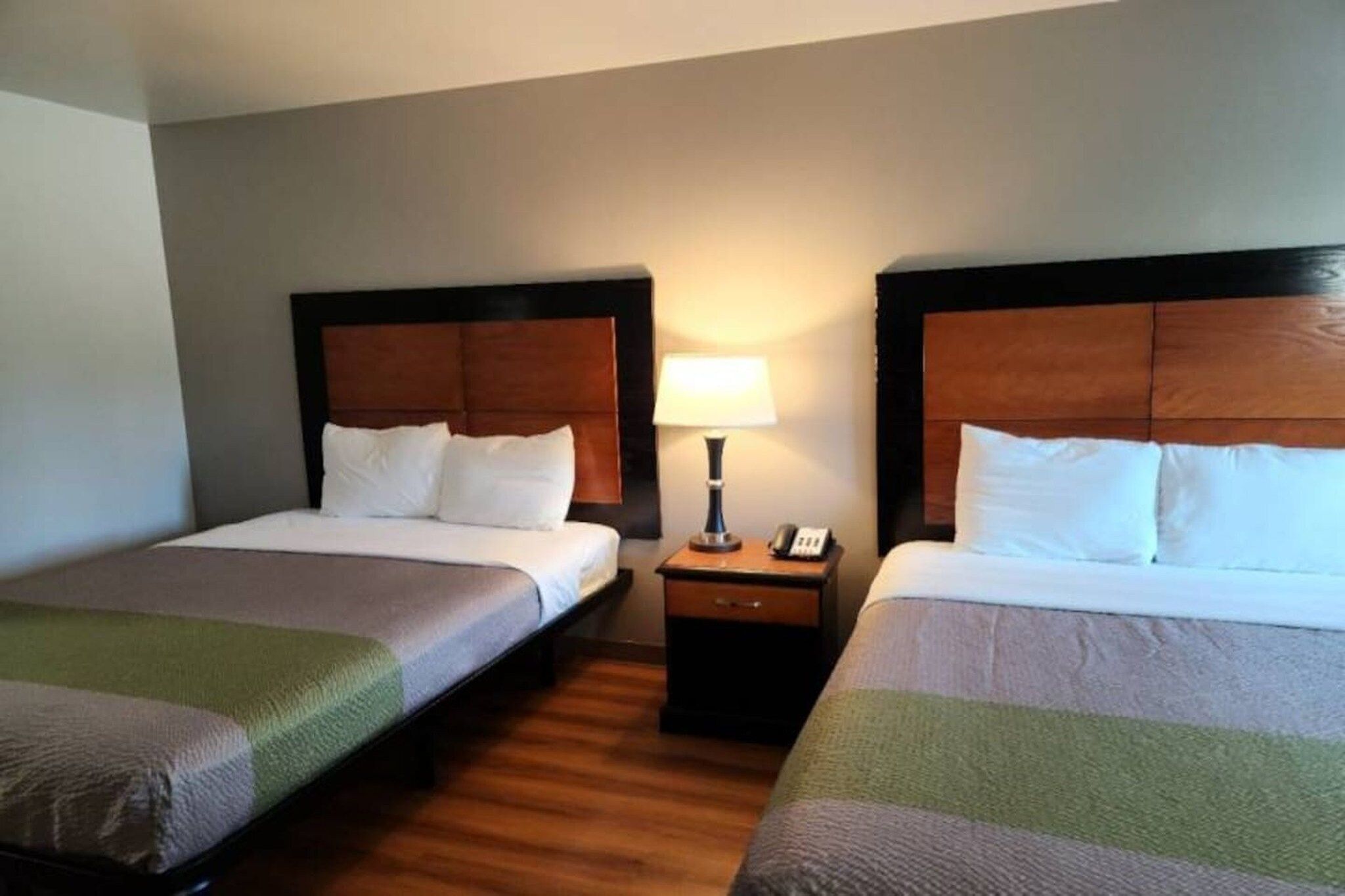 A hotel room with two single beds, a nightstand with a lamp, and a telephone.